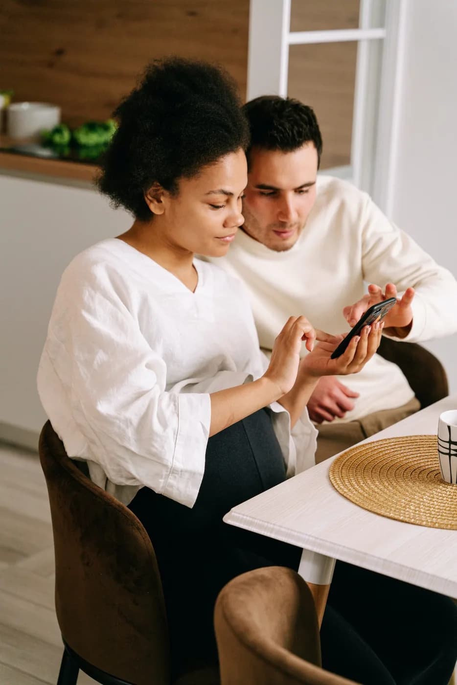 A couple at the table looking at a phone together