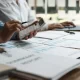 Des professionnels collaborent sur un ordinateur portable et des documents, illustrant un environnement de travail dynamique.