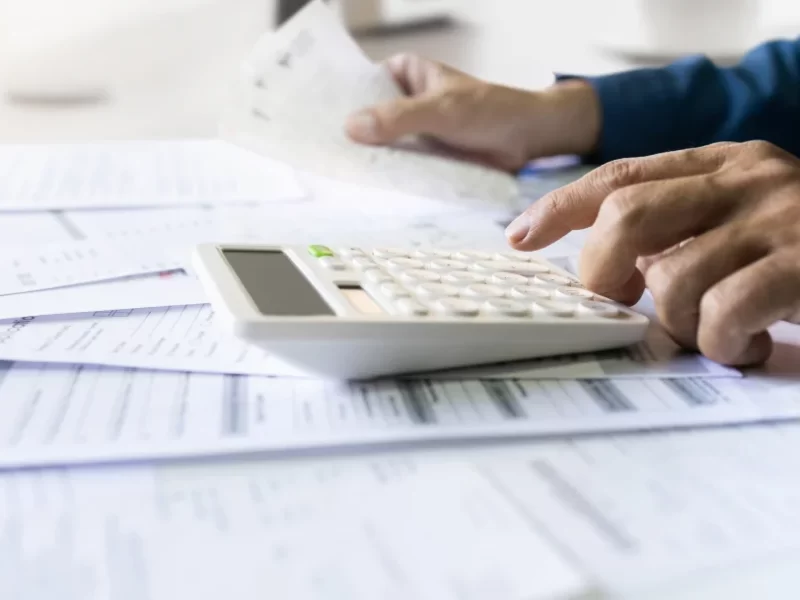 A person calculating figures on a calculator, symbolizing financial planning for a guaranteed acceptance personal loan.