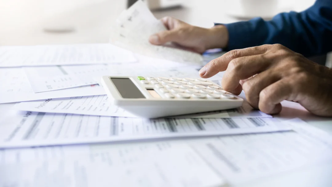 A person calculating figures on a calculator, symbolizing financial planning for a guaranteed acceptance personal loan.