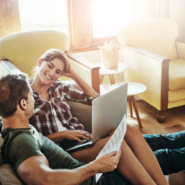 A man and woman on a couch, using a laptop to explore options for a guaranteed acceptance personal loan.