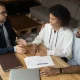 Trois personnes assises à une table, utilisant un ordinateur portable et des documents, discutent de prêts privés au Québec.