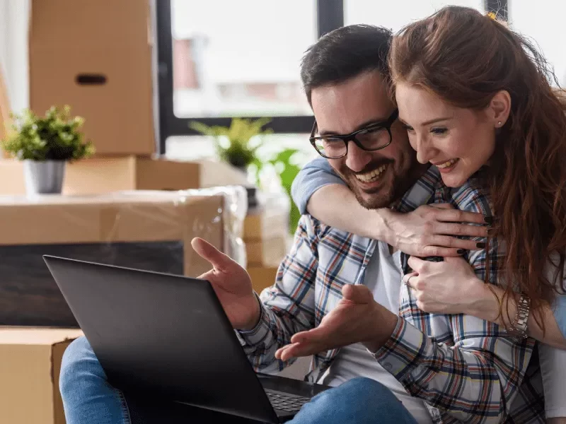 A man and woman sitting on a couch with a laptop