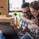 A man and woman sitting on a couch with a laptop