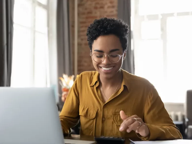 Une femme souriante utilisant son ordinateur portable.