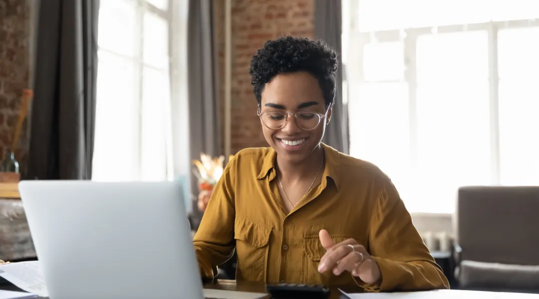 Une femme souriante utilisant son ordinateur portable.