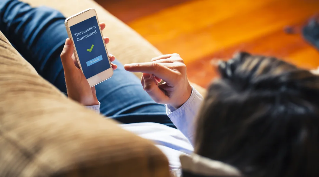 Une femme consulte ses e-mails sur son smartphone, illustrant l'utilisation moderne de la technologie pour la gestion des finances.