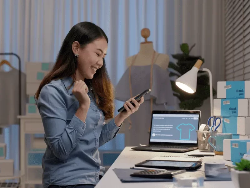 Une femme utilise son téléphone assise à un bureau