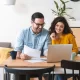 Un homme et une femme assis à une table avec un ordinateur portable