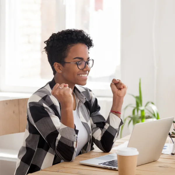 A woman wearing glasses sits at a desk, focused on her laptop, with financial documents related to a line of credit nearby.
