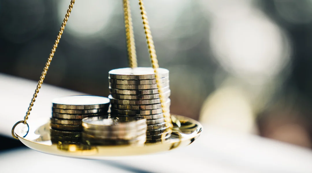 A balance scale weighing coins, symbolizing the concept of indebtedness and financial balance.