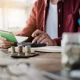 Un homme utilise une calculatrice pour évaluer ses revenus en lien avec un prêt personnel.